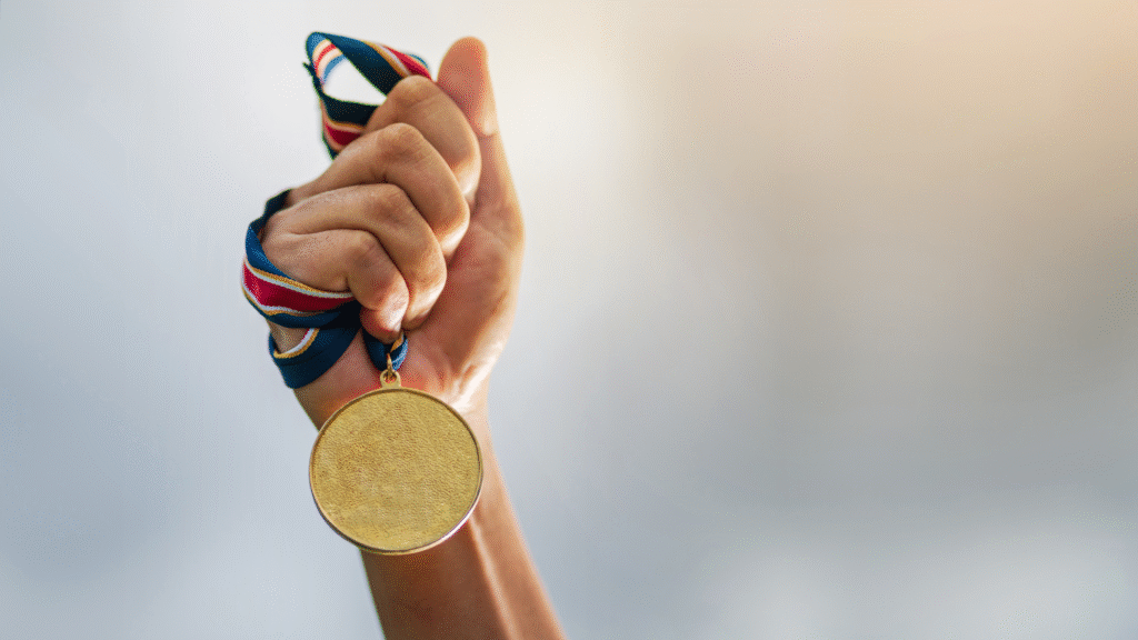 Banner _ Mão segurando uma medalha - Psicologia no Esporte
